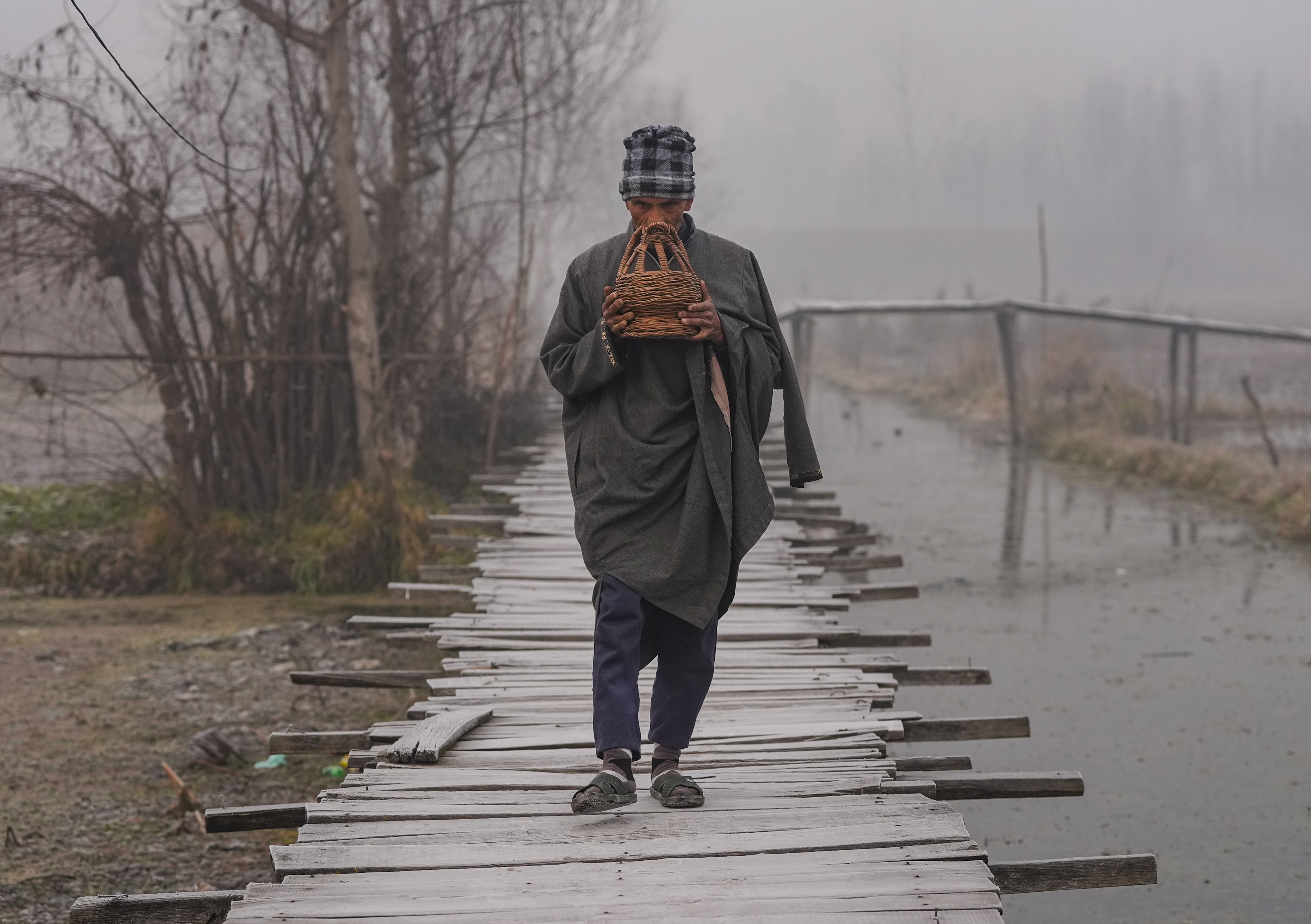 तस्वीर जम्मू-कश्मीर के श्रीनगर की है। यहां पर डल झील से गुजरता व्यक्ति कांगड़ी के साथ नजर आया।