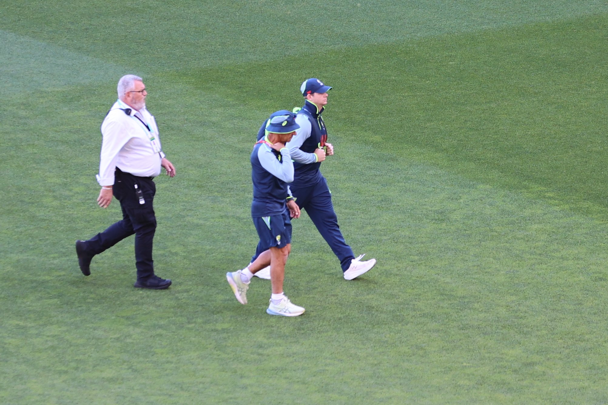 मैच शुरू होने से पहले स्टाफ के साथ मैदान से बाहर जाते स्टीव स्मिथ (दाएं कैप लगाए हुए)।