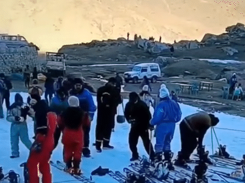 गाड़ियों में लाई गई बर्फ के बीच स्कीइंग करते हुए टूरिस्ट।