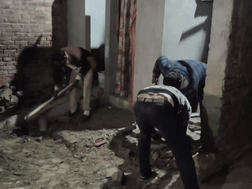 घर के आंगन में सेप्टिक टैंक की खुदाई करते मजदूर।