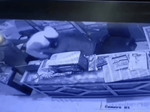 दुकान मालिक को कुर्सी से घसीट कर नीचे गिरा कर मारते हुए। दूसरा बदमाश गल्ले से निकालने के लिए आगे गढ़ता हुआ।