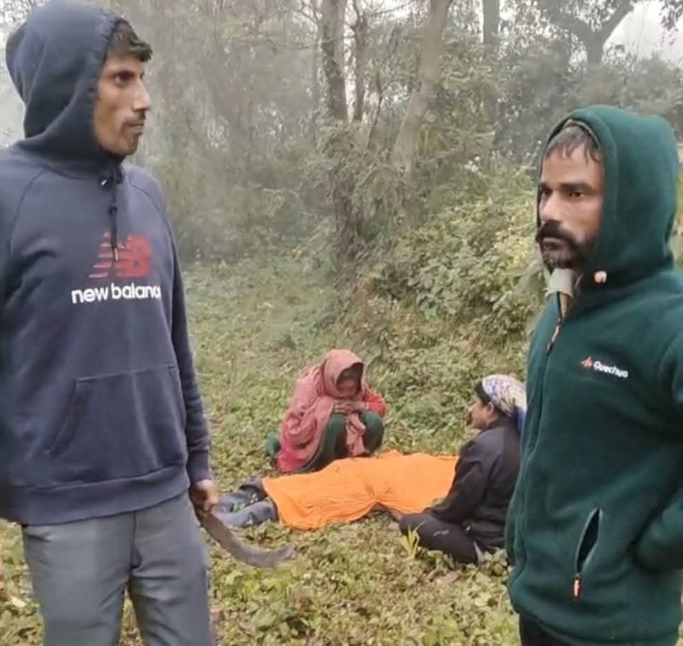 तेंदुए के हमले में गंभीर रूप से घायल व्यक्ति के पास बैठी महिलाएं और अपनी सुरक्षा को हाथ में हथियार लेकर स्थानीय लोग।