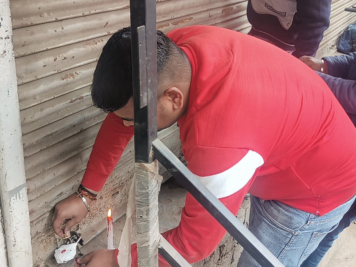 करनाल में दुकानों को सील करते कर्मचारी