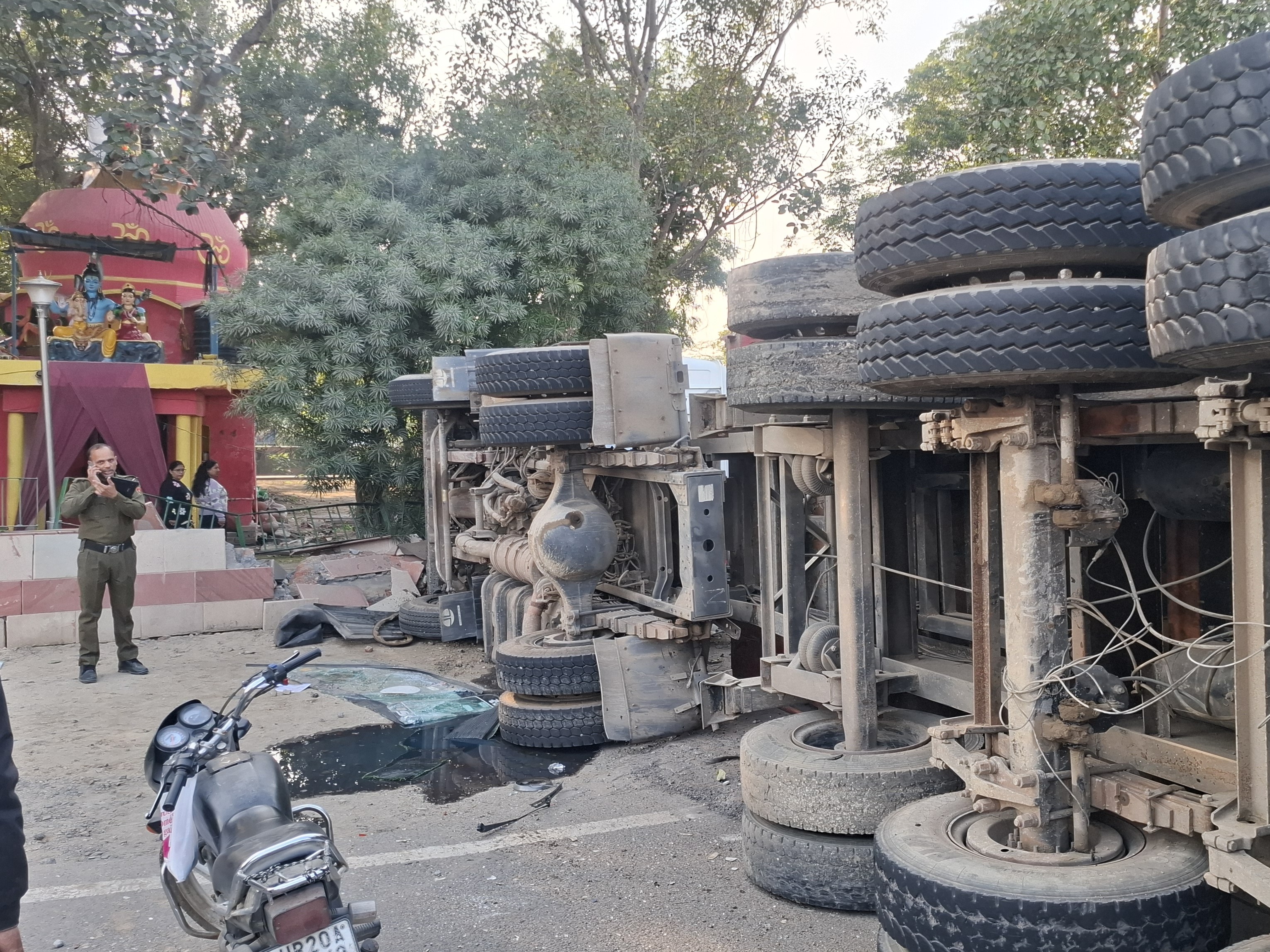 मंदिर की दीवार के साथ पलटा पड़ा ट्राला।