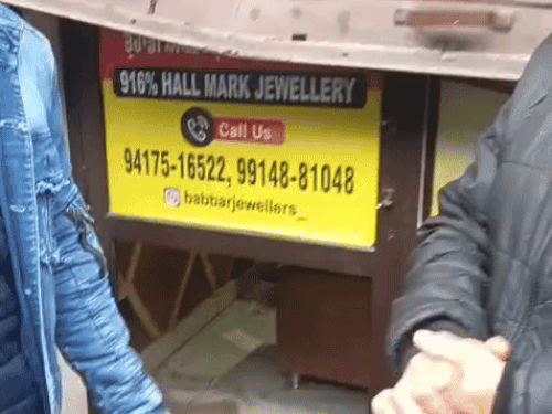 चोरों द्वारा तोड़े गए शटर को दिखाते दुकानदार।