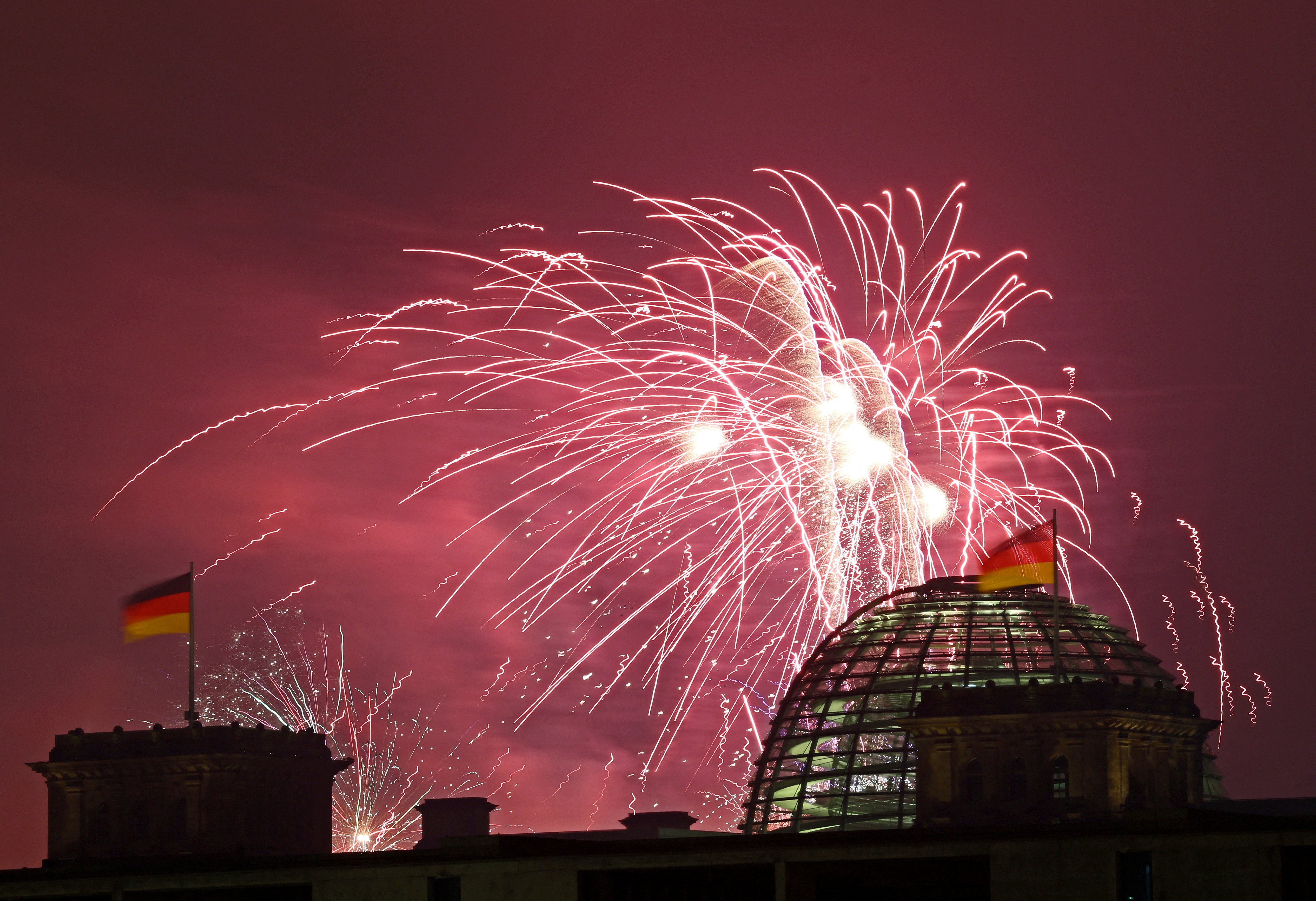 जर्मनी के बर्लिन में रीचस्टैग बिल्डिंग के कांच के गुंबद के ऊपर आतिशबाजी।