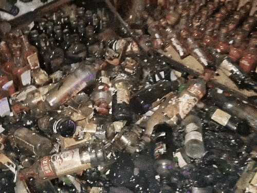 ठेके के अंदर गिरी शराब की बोतलें।