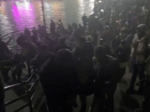 व्यक्ति को पकड़ घाट की सीढ़ियों से उसे बाहर लेकर जाते पुलिसकर्मी।