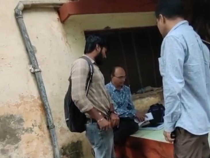 नीचे बैठे नीले शर्ट में एसडीओ पैसों को पेपर में लपेटते हुए।