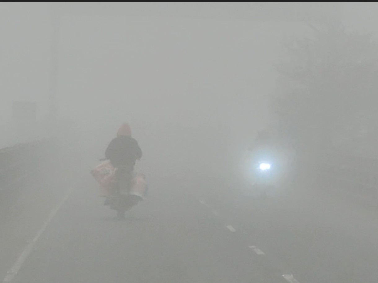 कोहरे के कारण सुबह हेडलाइट जलाकर निकले बाइक सवार