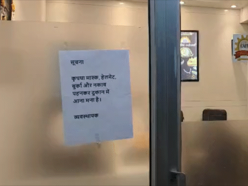 दुकानों के गेट पर लगे पोस्टर में लिखा है- मास्क, हेलमेट, बुर्का और नकाब पहनकर आना मना है।