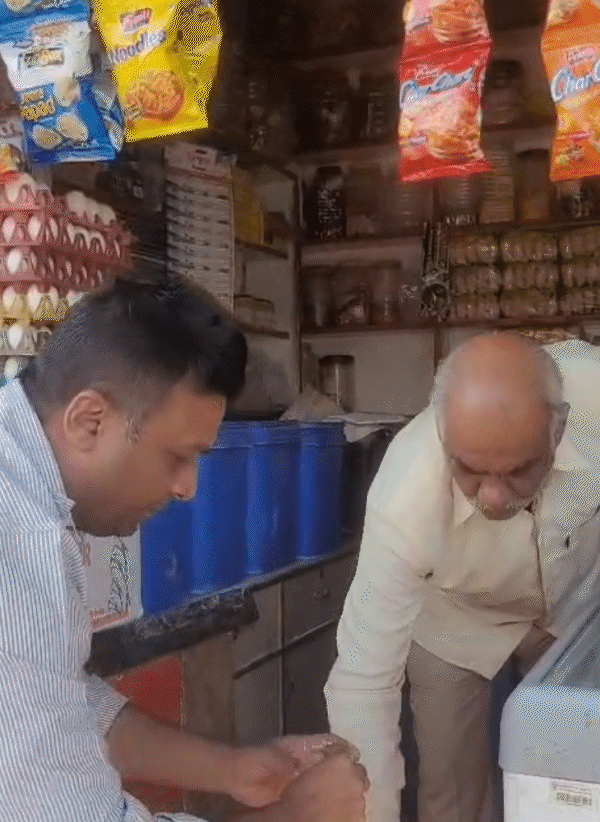 दुकानदार इरफान मियां ने ग्लास में हैंडपंप का पानी भरकर दिखाया।