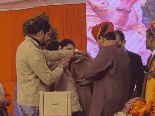 Brother and sister from Haryana helping Brij Bhushan Sharan Singh put on a jacket.