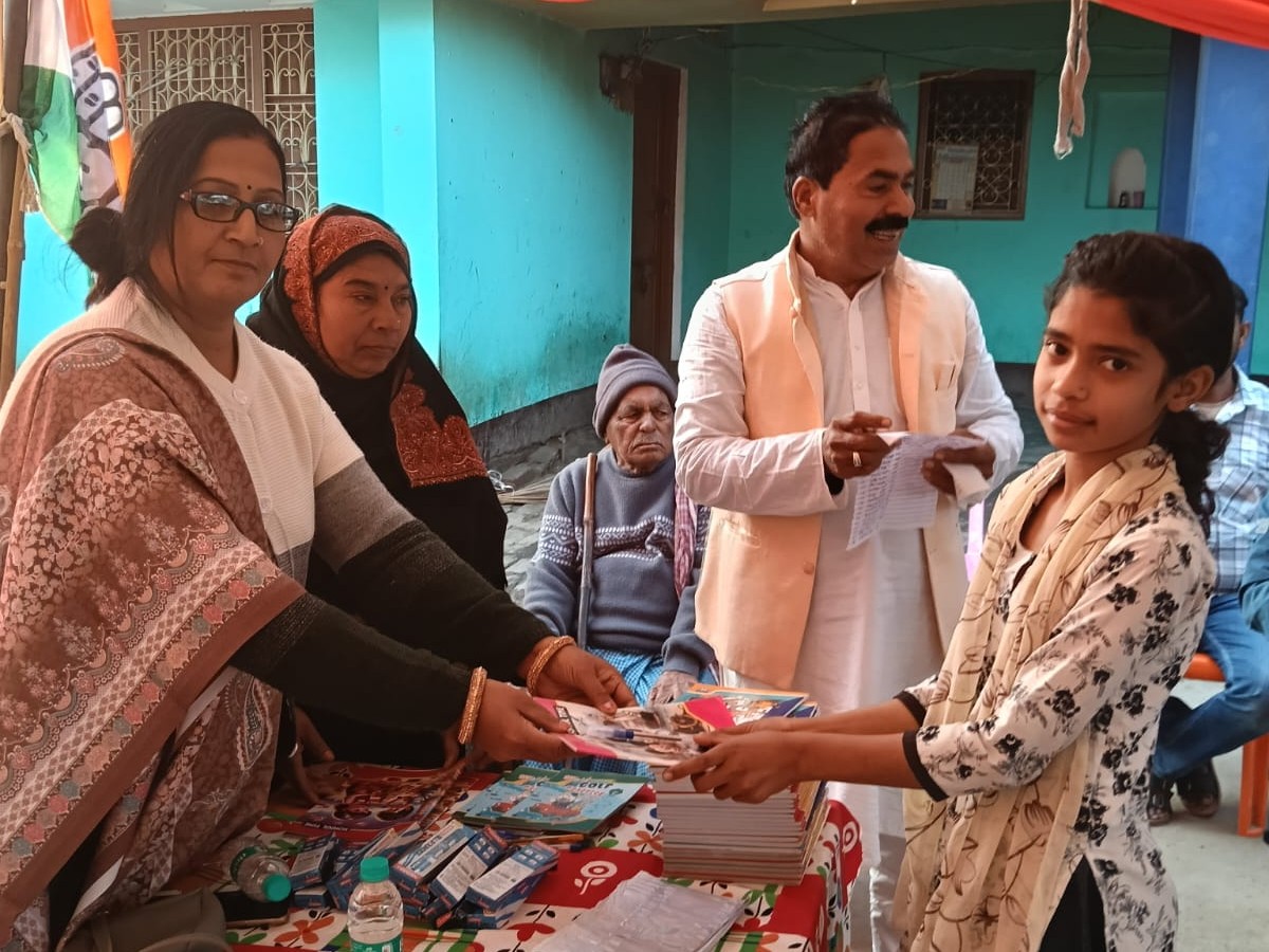 बच्चे को कॉपी बांट रही महिला शिक्षिका।