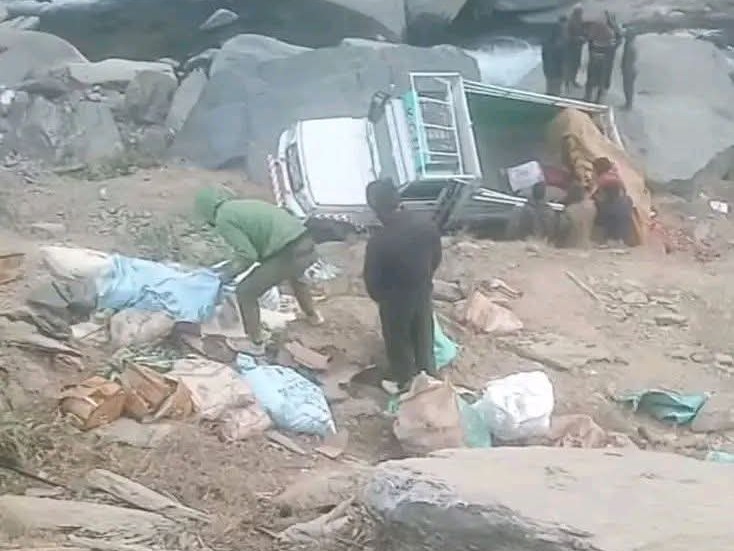 खाई में गिरी पिकअप से गिरे सामान को संभालते हुए।