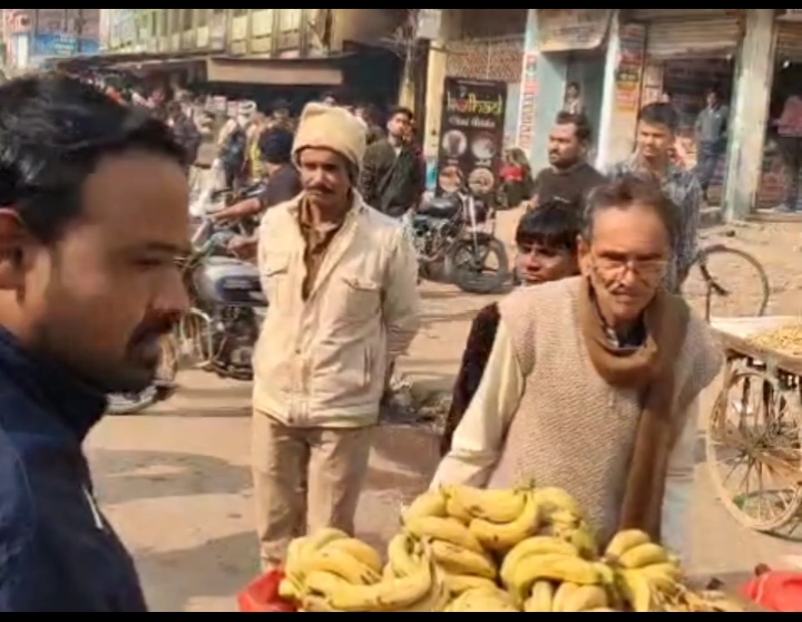 फुटपाथ से हाथठेला ले जाता बुजुर्ग।