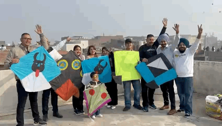 एक मकान की छत पर पतंग के साथ लोग।