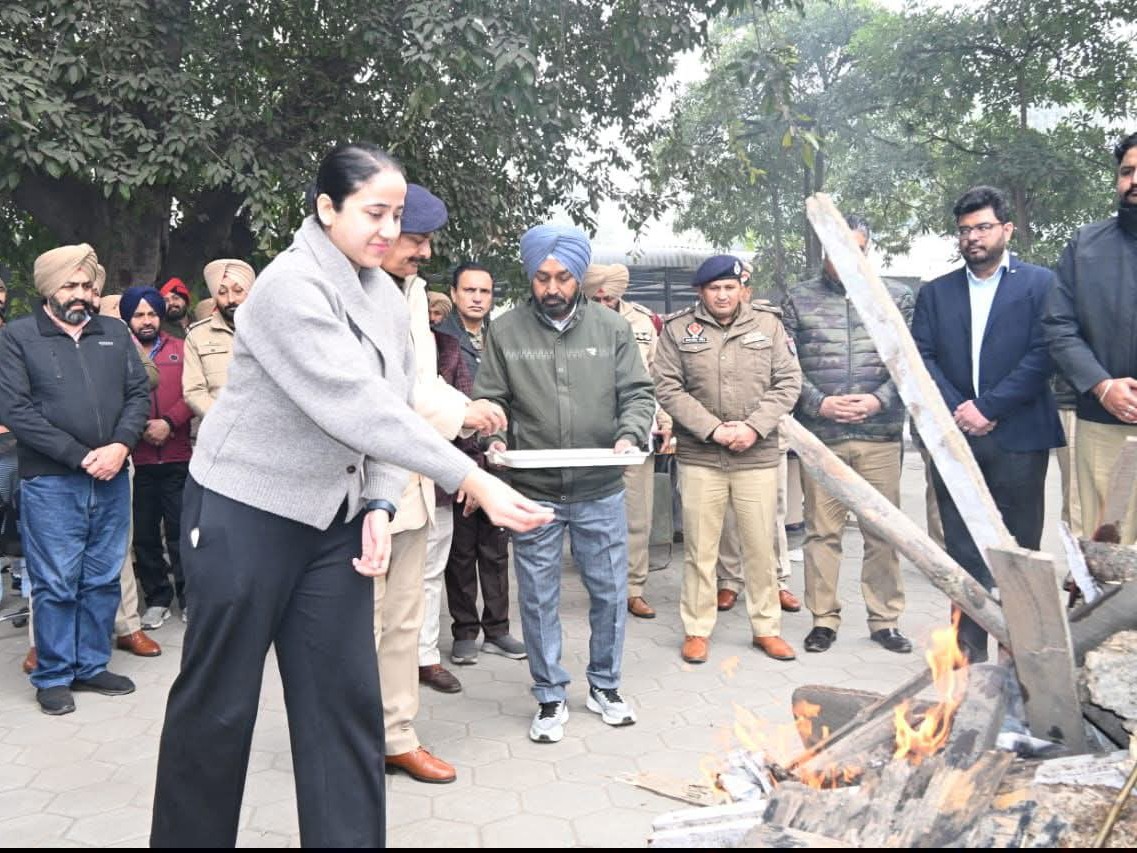लोहड़ी की अग्नि में मूंगफली आदि डालती युवती।