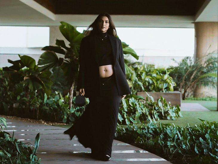 ব্লেজারে ডাবল কলার এবং নচ ল্যাপেল দেখা যাচ্ছে। নিচে সে প্যান্টের বদলে পেন্সিল স্টাইলের ম্যাক্সি স্কার্ট পরে আছে।