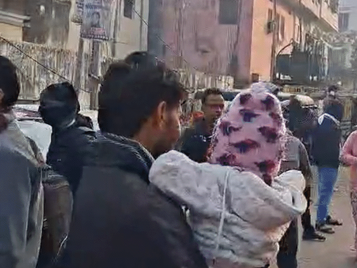 एग्जाम सेंटर के बाहर छोटे बच्चों को गोद में रखते अभिभावक।