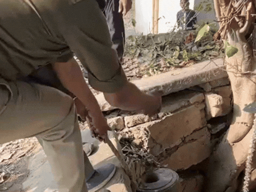 कुएं से शव को निकालते पुलिसकर्मी।