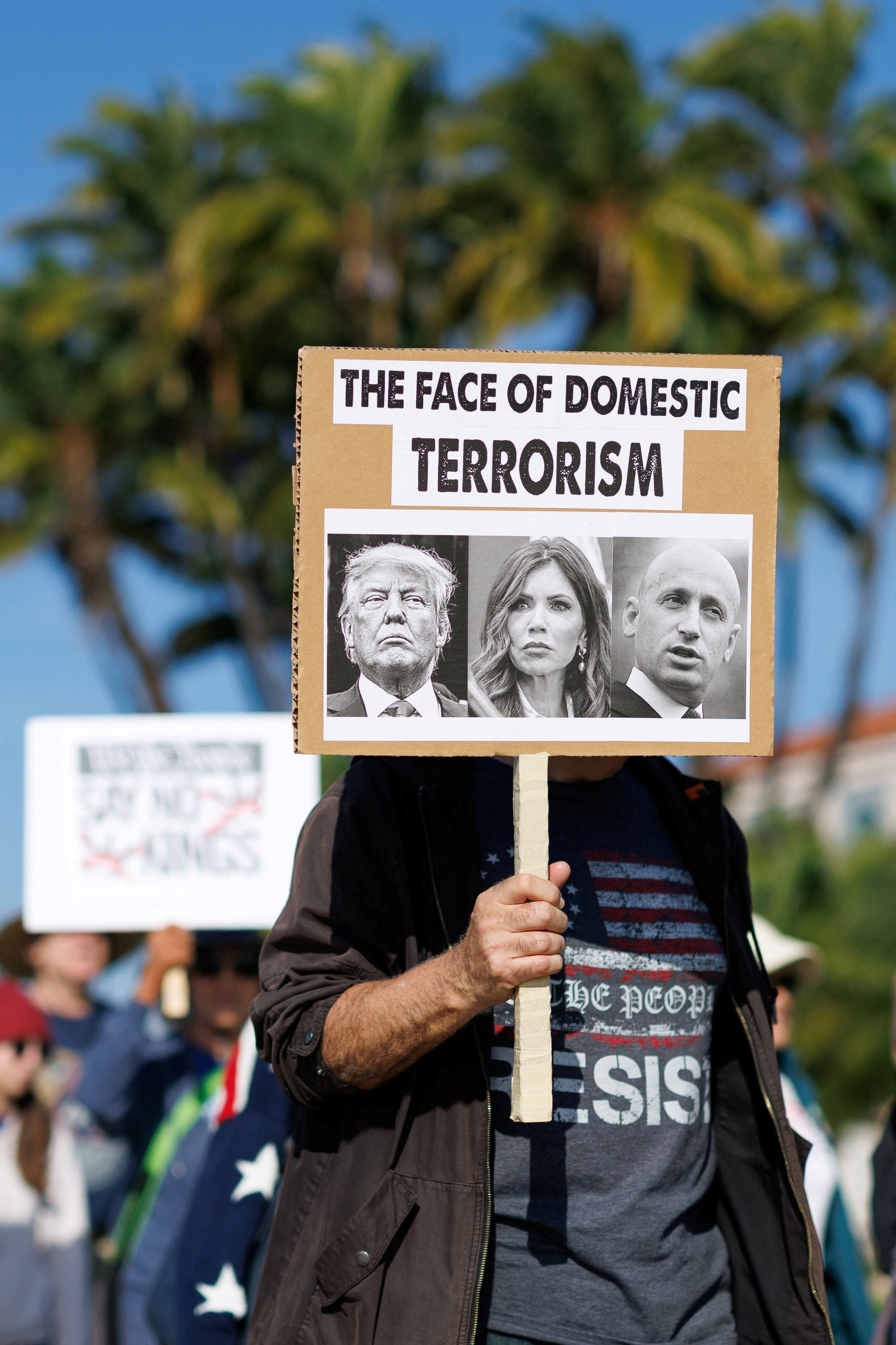 तस्वीर में एक शख्स हाथ में तख्तियां लेकर ट्रम्प को आतंकवाद के चेहरे के तौर पर बता रहा है।