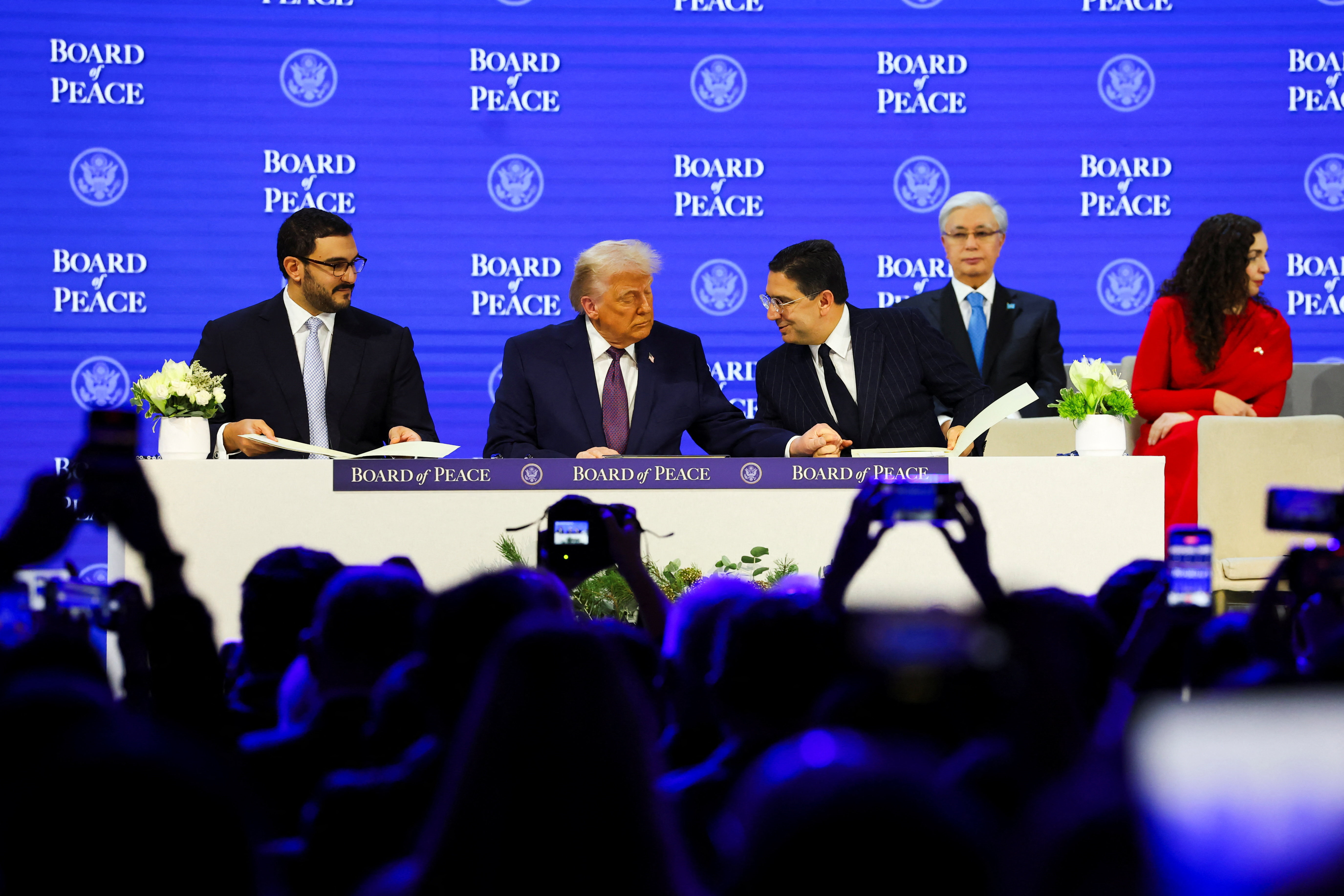 बोर्ड ऑफ पीस लॉन्च करते वक्त ट्रम्प अपने साथ मंज पर मौजूद अधिकारियों से बात करते हुए।