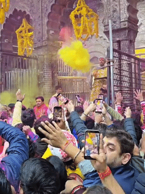 सेवायत मदिर के अंदर से श्रद्धालुओं पर अबीर और रंग बरसाते हुए।
