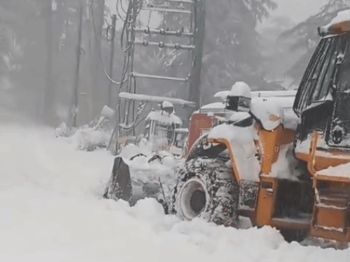 सड़क से बर्फ को हटाते हुए जेसीबी।