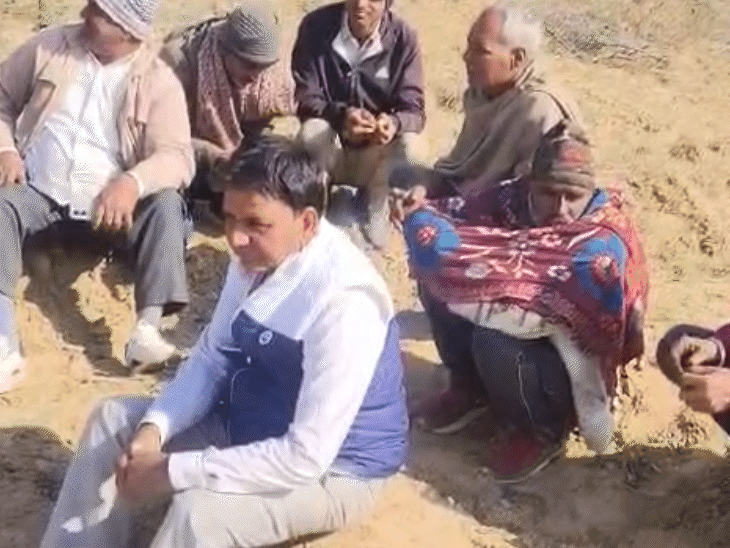 युवक की मौत के बाद खेत के पास बैठे ग्रामीण