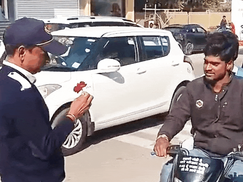 बाइक सवार को बिना हेलमेट चलाने पर चालान के बदले गुलाब देते ट्रैफिक ऑफिसर।