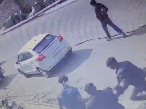 युवक को घसीटकर कार की तरफ लेकर जाते बदमाश।