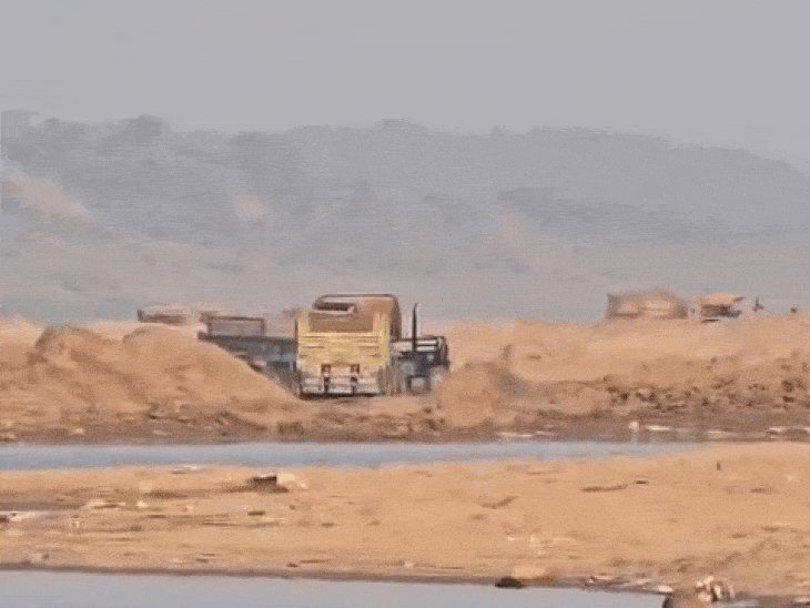 मशीनों से रेत निकालकर ले जाते वाहन। किनारे पर इतने ऊंचे ढेर लगे हैं कि डंपर छिप जाए।