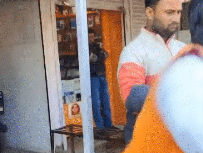 जमीन पर गिरी महिला को संतोष ने लकड़ी से पीटा।