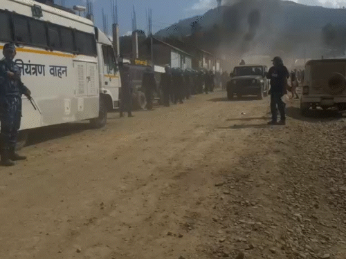 आग में घिरे घरों से सामान निकालने में लोगों की मदद करते हुए सुरक्षाकर्मी।