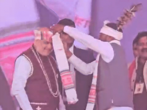 मच पर कौड़ी की माला और पगड़ी पहनाकर अमित शाह का स्वागत किया गया।