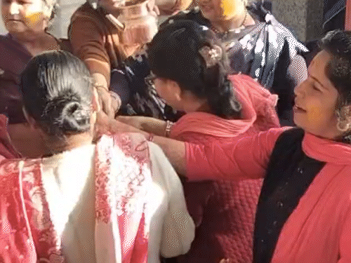 एक-दूसरे को हल्दी लगाती हुई महिलाएं।
