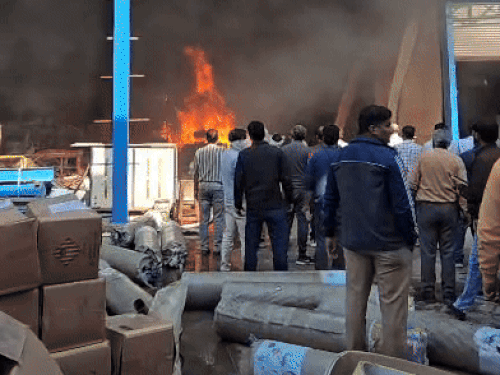 आग पर काबू पाते हुए फायर ब्रिगेड कर्मचारी।