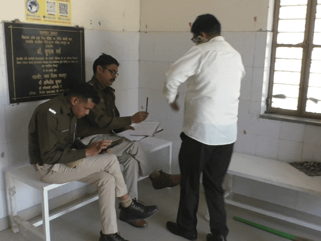 पुलिसकर्मी शवों के पोस्टमार्टम की कार्रवाई करते हुए।