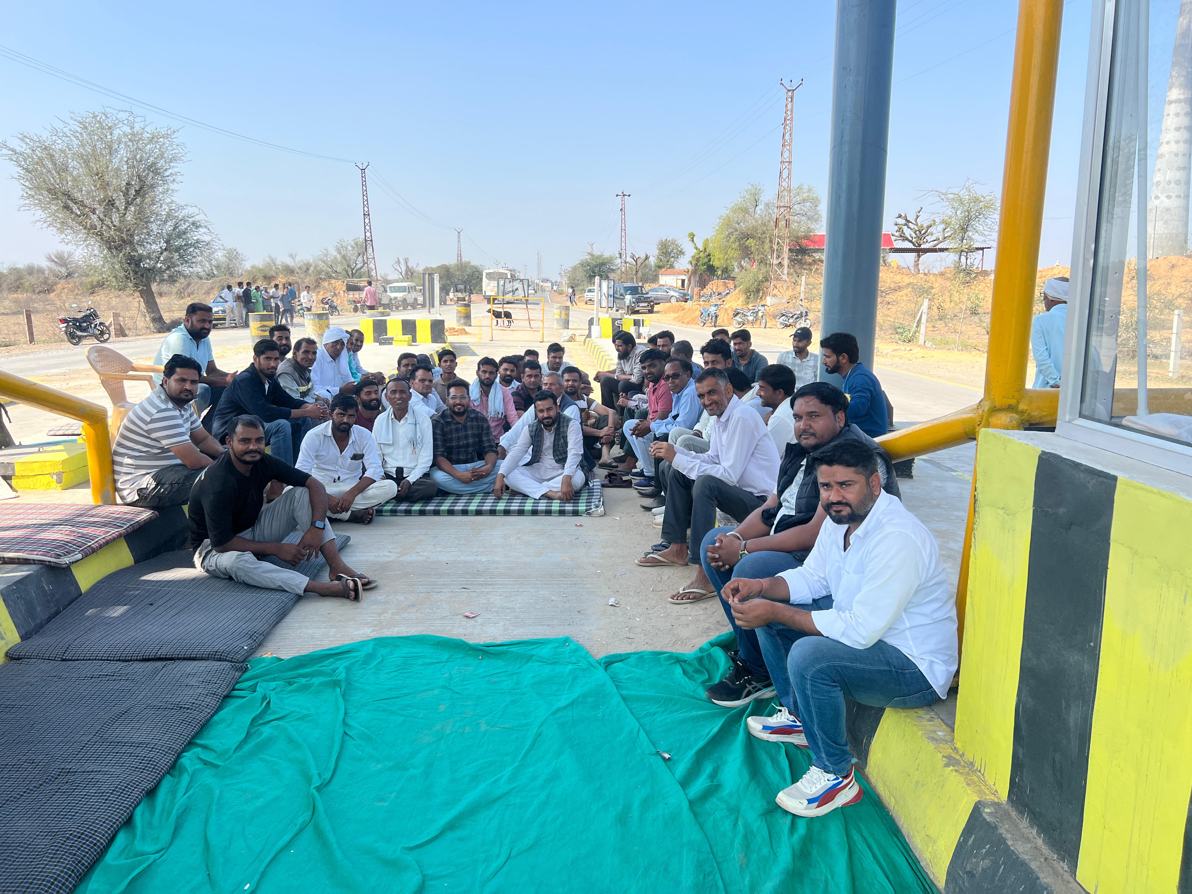 टोल प्लाजा क्षेत्र में धरने पर बैठे ग्रामीण