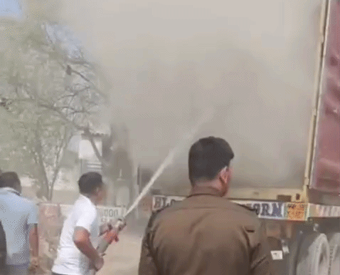 आग को बुझाते हुए फायर बिग्रेड के कर्मचारी।