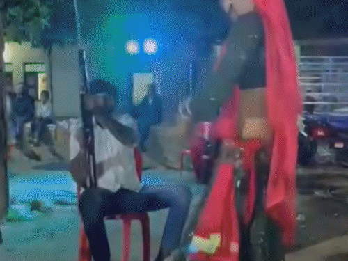 कुर्सी पर बैठा युवक राइफल से हवाई फायर करता रहा।