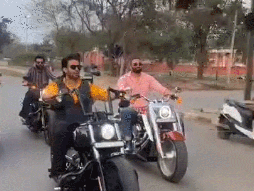 राहगीर को हाथ हिलाकर आवाज मारते सिंगर मनकीरत औलख।