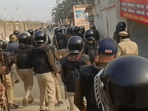 पथराव कर रहे मजूदरों को रोकते पुलिस कर्मचारी।