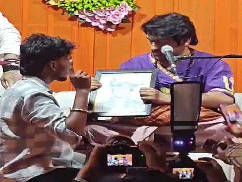 गुरुग्राम में एक युवक द्वारा तैयार किए चित्र को देखते धीरेंद्र शास्त्री।