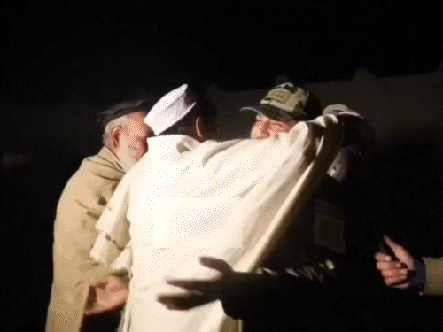 पाकिस्तानी हमले में मारे गए लोगों के परिजन से मिलते अफगान सैनिक।