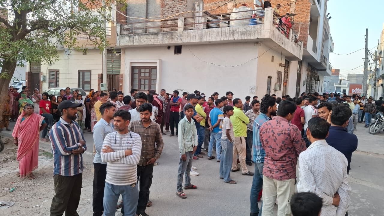 इलाके के लोगों घर के बाहर खड़े देखते हुए