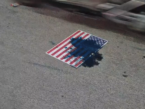 अमेरिका के झंडे में स्याही फेंकी गई। सड़कों पर पोस्टर चिपकाए गए।