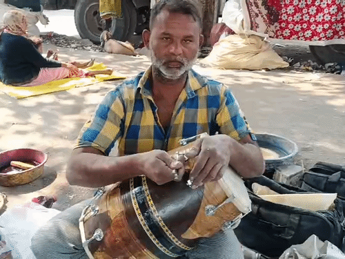 ढोलक के पेंच कसता कारिगर।
