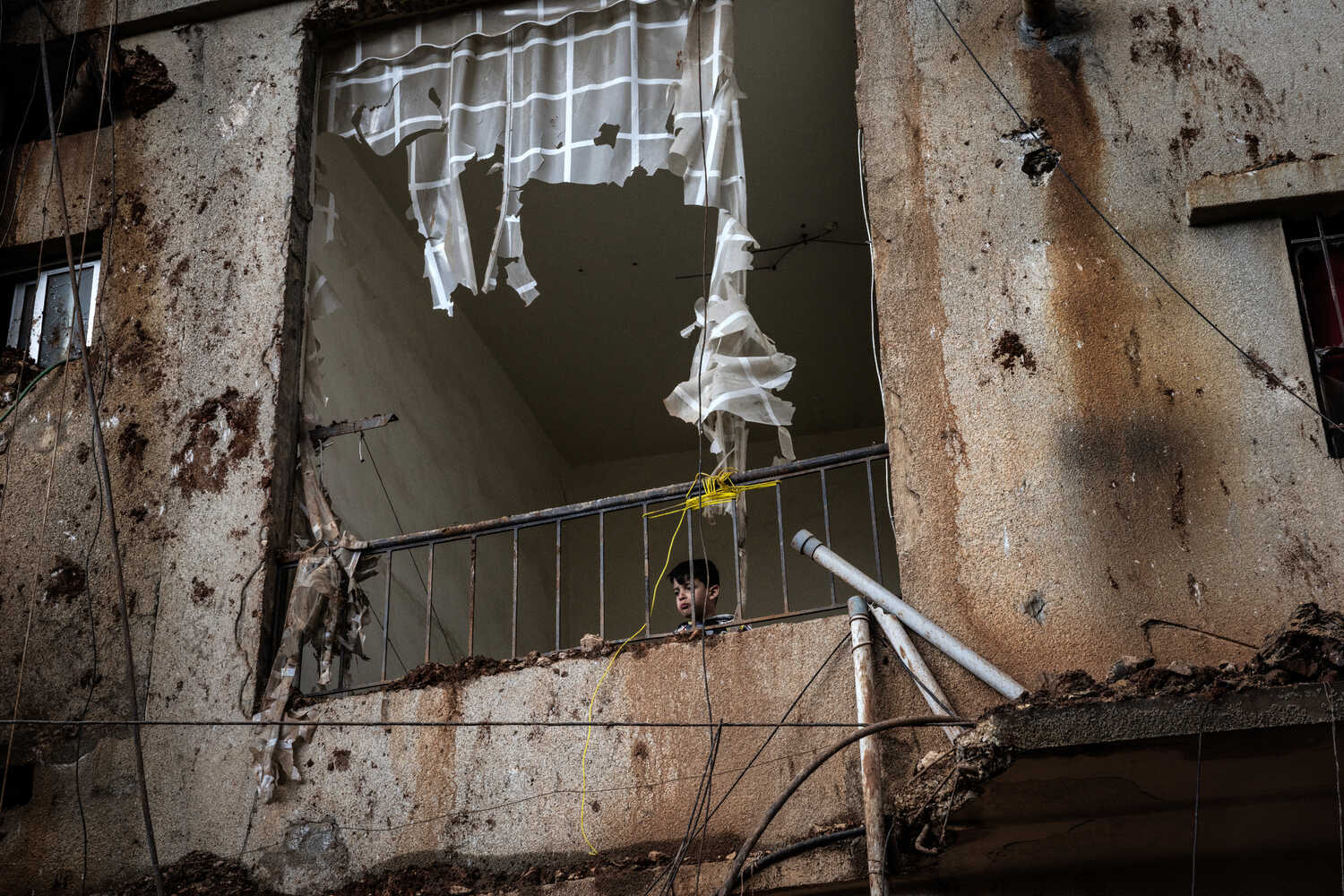 लेबनान में हमले के बाद बालकनी से बाहर झांकता बच्चा।